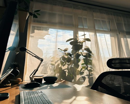 Home office setup with soft indirect sunlight filtering through curtains