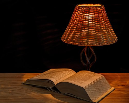 Open book under a warm desk lamp at night